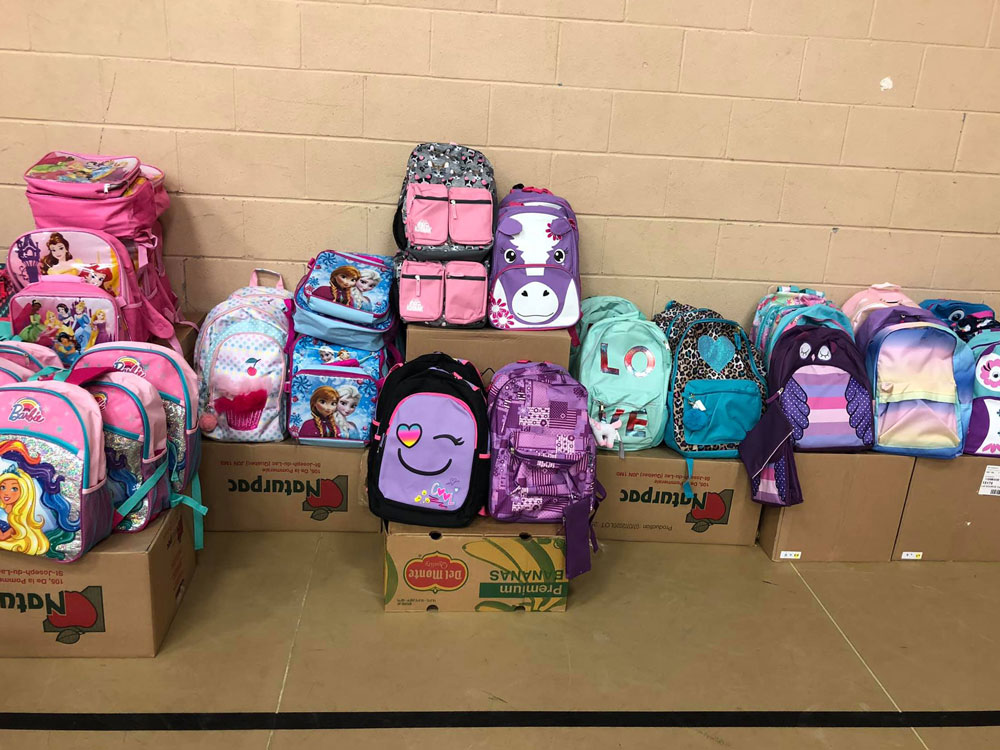 children's school bags laid out on the floor for the annual back to school backpack giveaway